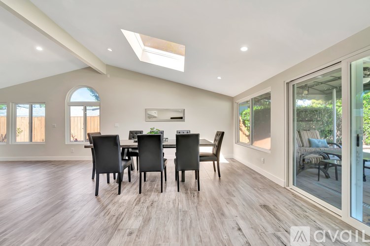 A dining room with a table and chairs and a skylight.