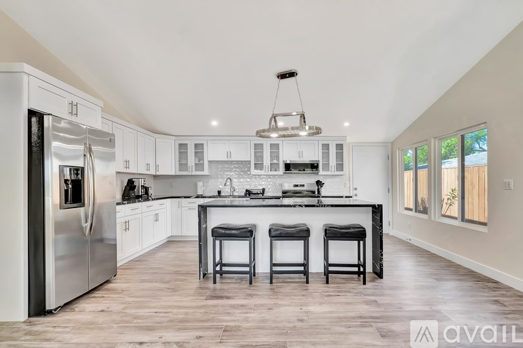A modern kitchen with a large island and stools.