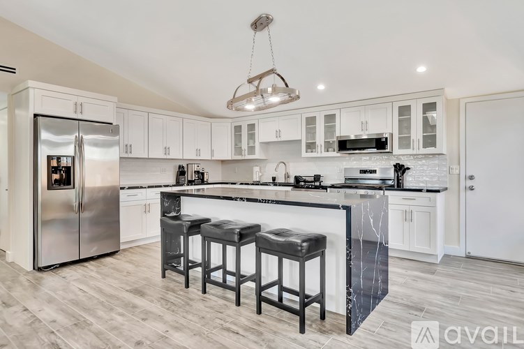 A kitchen with a refrigerator, stove, and bar stools.