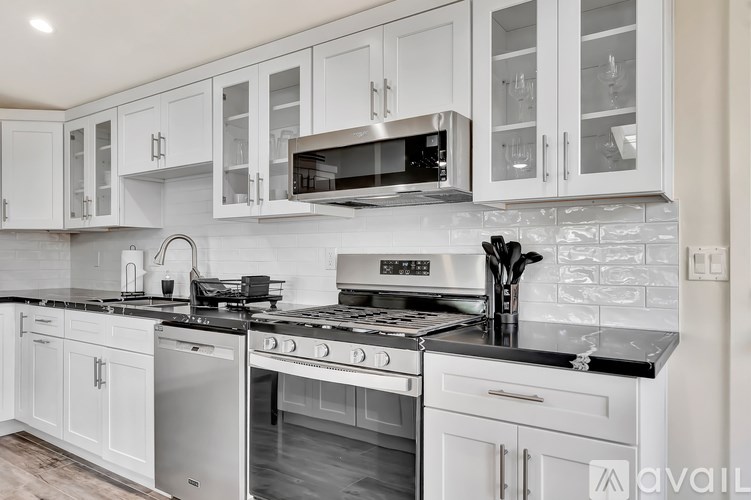 A kitchen with white cabinets and black countertops.