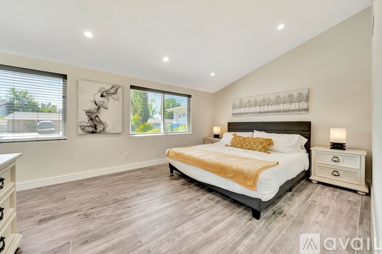 A bedroom with a large bed, a nightstand, and two framed pictures on the wall.