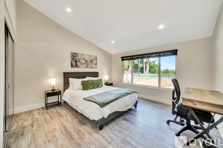 A bedroom with a large bed, a desk, and a chair.