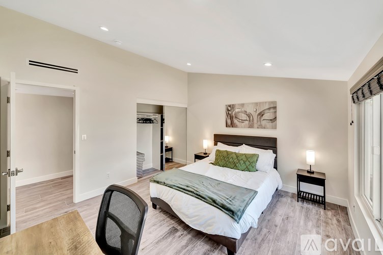 A bedroom with a bed, chair, and painting on the wall.