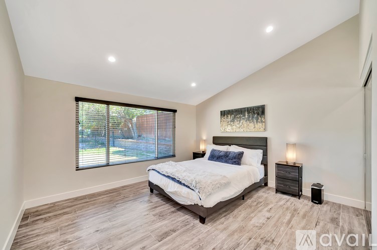 A bedroom with a large bed and a window with blinds.