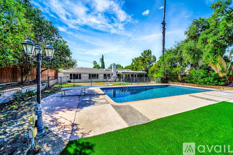 A pool surrounded by a green lawn and trees.