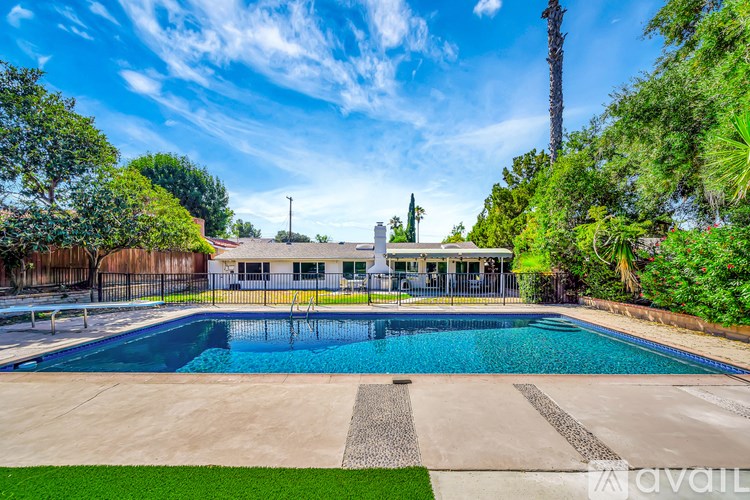 A large swimming pool surrounded by a fence and trees.