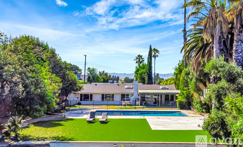 A house with a pool surrounded by greenery.