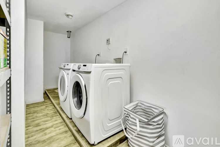 A laundry room with a washer and dryer and a striped laundry basket.