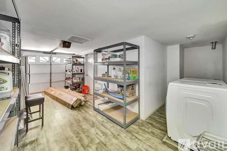 A room with a white washing machine and a shelving unit with various items on it.