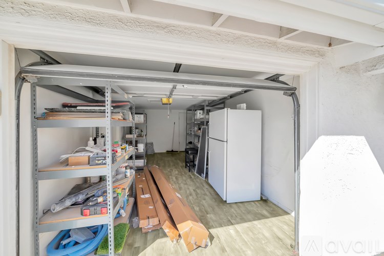A storage room with a white refrigerator and shelves filled with various items.