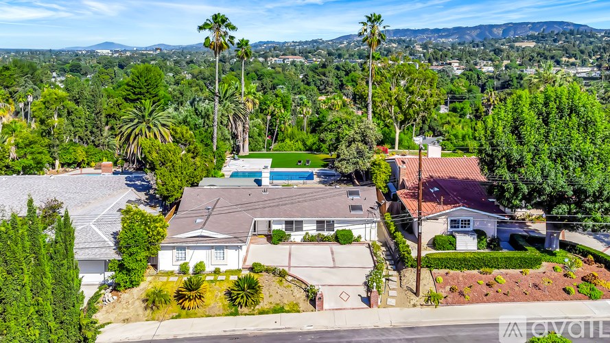 A house with a pool surrounded by trees and a mountain in the distance.