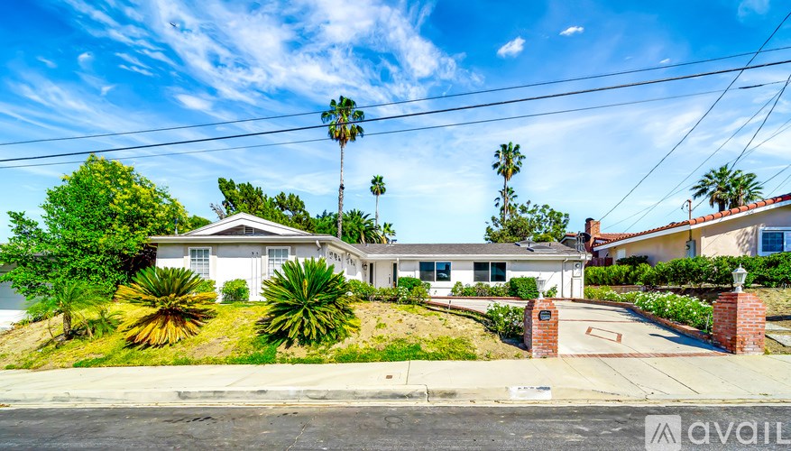 A house with a white exterior and a red brick pillar in front is for sale.