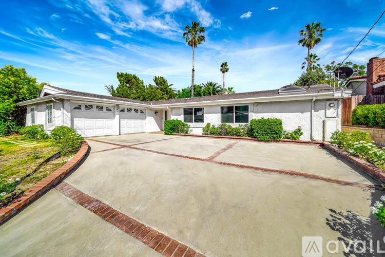 A house with a driveway and palm trees in the background.