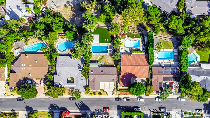 A bird's eye view of a residential area with houses and swimming pools.
