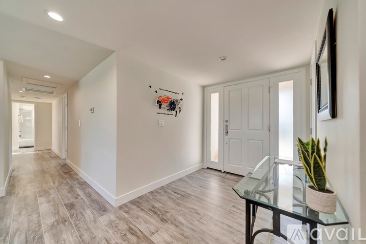 A hallway with a glass table and a plant on it.