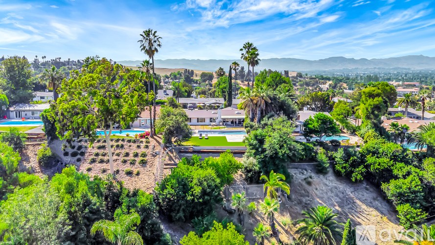 A view of a residential area with houses, trees, and a pool.