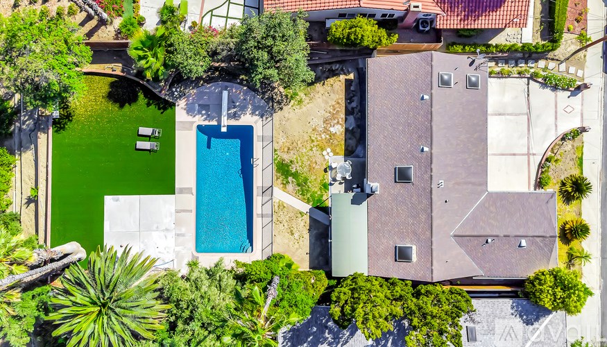 A house with a green lawn and a blue pool.