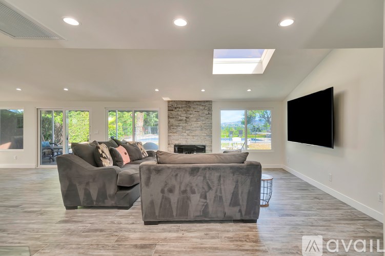 A modern living room with a grey sofa and a flat screen TV mounted on the wall.