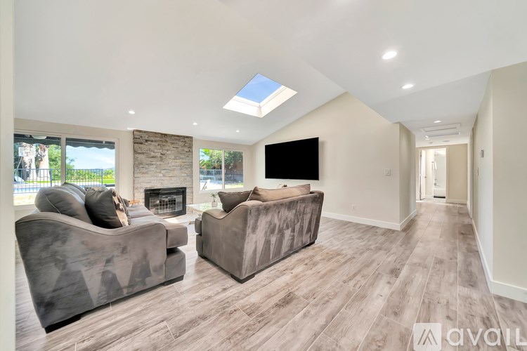 A spacious living room with a stone fireplace and a flat-screen TV.