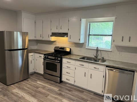 A kitchen with white cabinets and a stainless steel refrigerator.