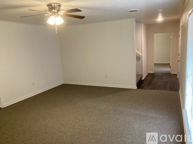 A room with a carpeted floor and a ceiling fan.