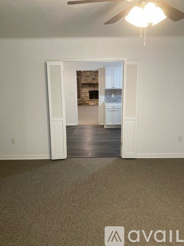 A room with a carpeted floor and a ceiling fan.