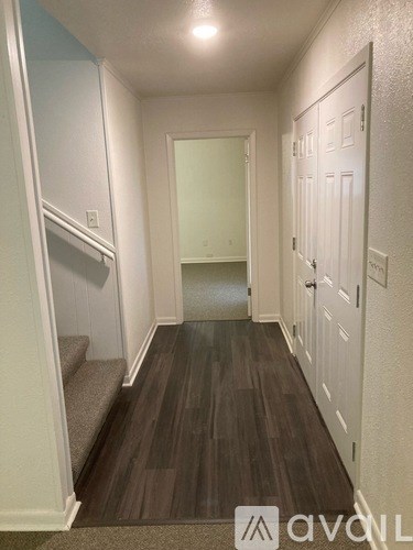 A hallway with wood floors and white walls.