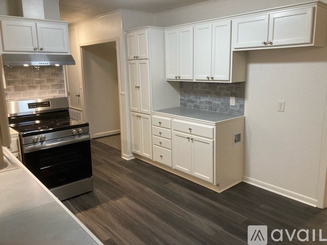 A kitchen with white cabinets and a stove top oven.