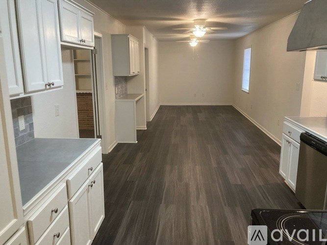 A kitchen with white cabinets and a grey countertop is available.