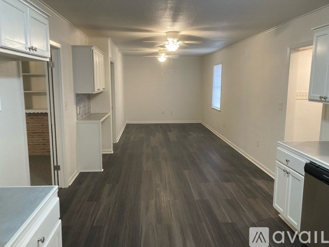 A kitchen with white cabinets and a wooden floor.
