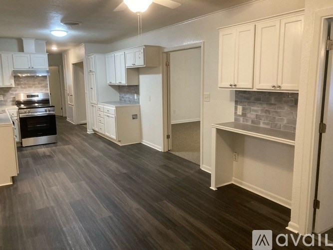 A kitchen with white cabinets and a grey floor.