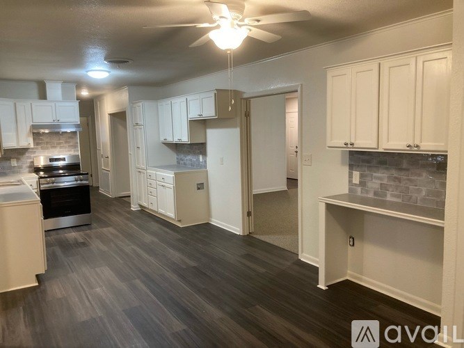 A kitchen with white cabinets and a wooden floor.