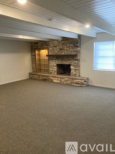 A room with a stone fireplace and a window.