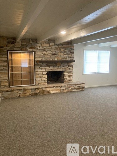 A stone fireplace with a window above it in a room.