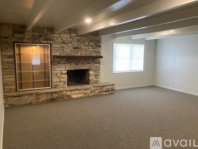 A room with a stone fireplace and a window.