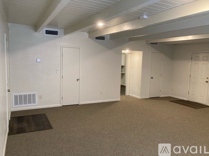A room with white walls and a carpeted floor with a brown rug.