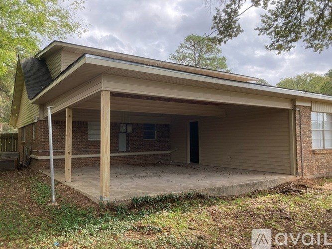 A detached garage with a covered porch and a brick wall.
