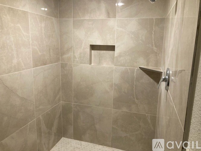 A shower area with a glass door and tiled walls.