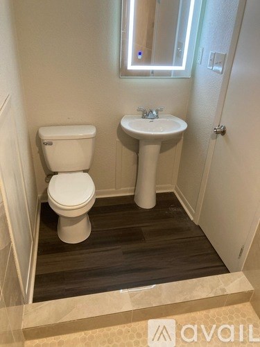 A bathroom with a toilet, sink and mirror.
