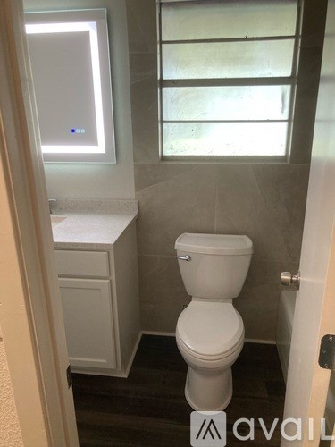 A white toilet in a bathroom with a window.