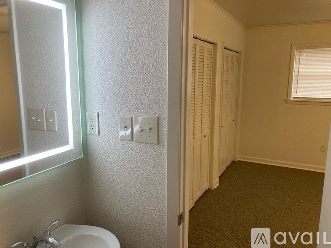 A bathroom with a sink, mirror, and light switches.