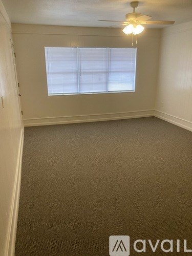 A room with a ceiling fan and a window with blinds.