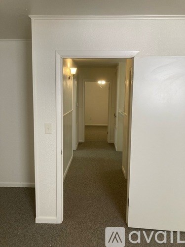 A hallway with a carpeted floor and white walls.