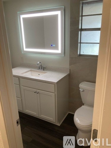 A white bathroom with a toilet, sink, and cabinet.