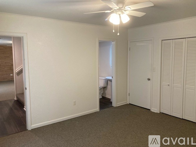 A room with a ceiling fan and carpeted floor.
