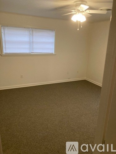 A room with a carpeted floor and a ceiling fan with lights.