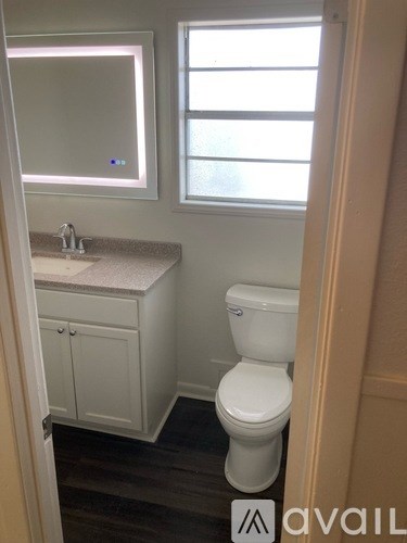 A white toilet in a bathroom with a sink and a window.