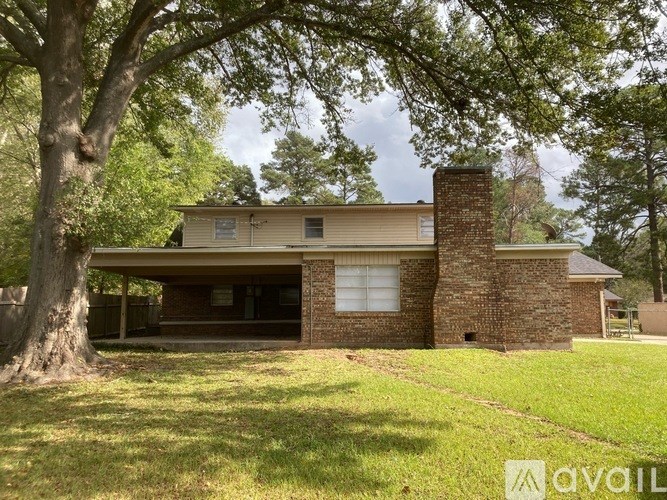 A house with a brick chimney is surrounded by trees.