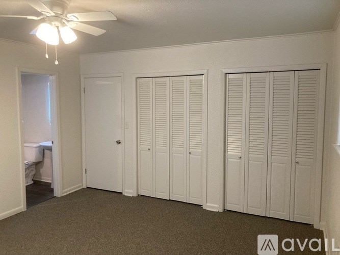A room with a ceiling fan and three closet doors.