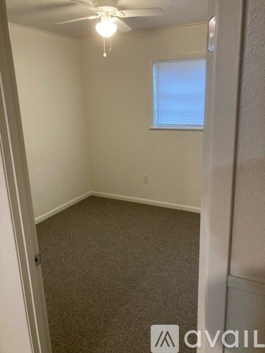A room with a ceiling fan and carpeted floor.